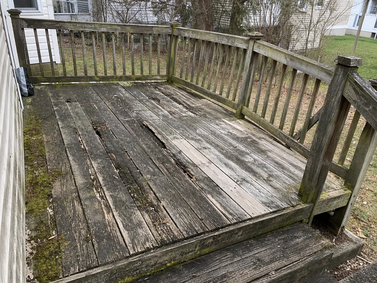 Rotting weathered deck boards and loose railing before the rebuild