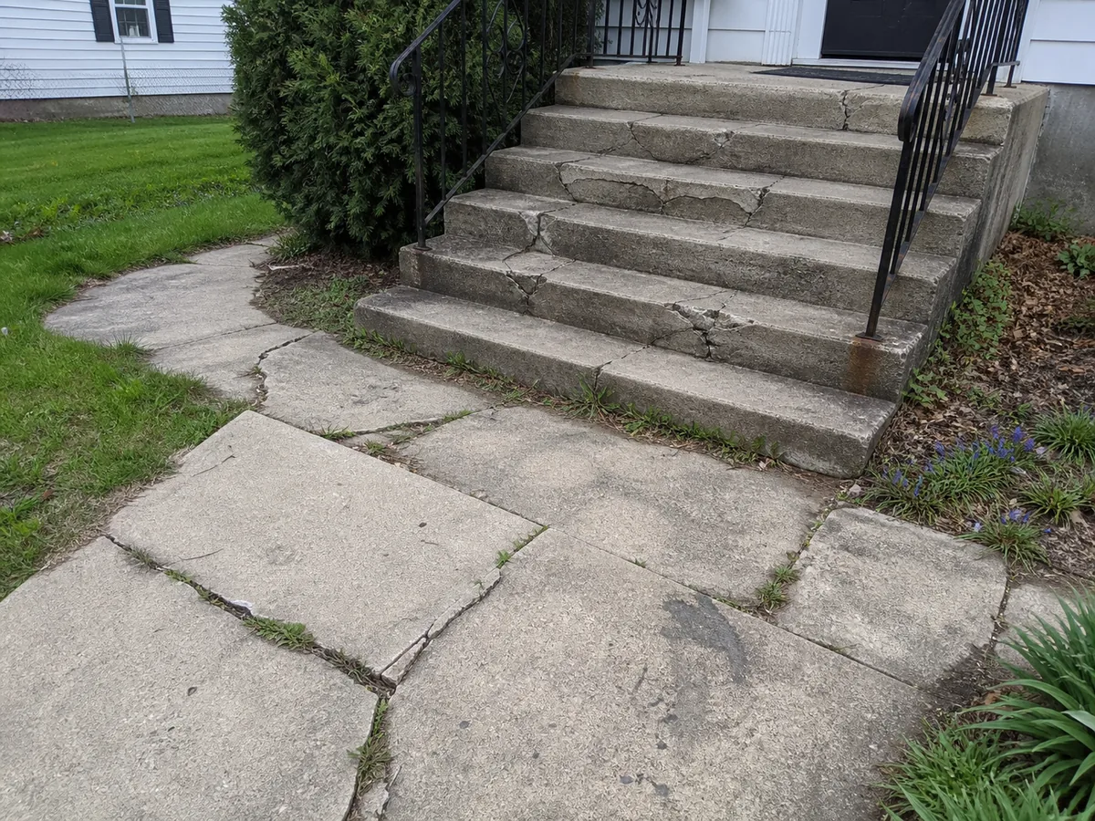 Cracked concrete walkway and crumbling front steps before the work