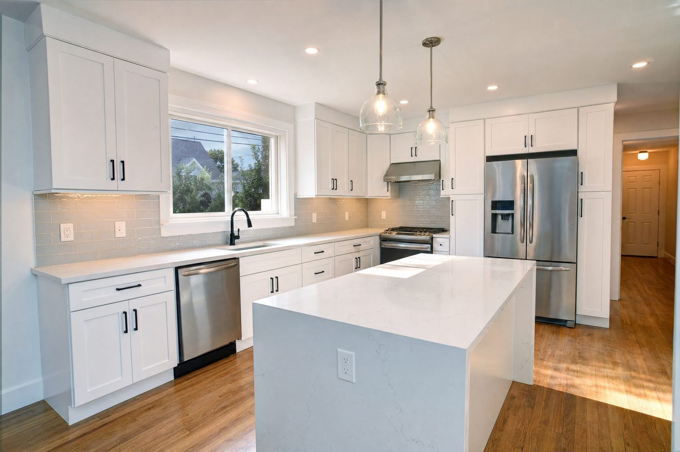 Remodeled kitchen with white shaker cabinets and quartz island